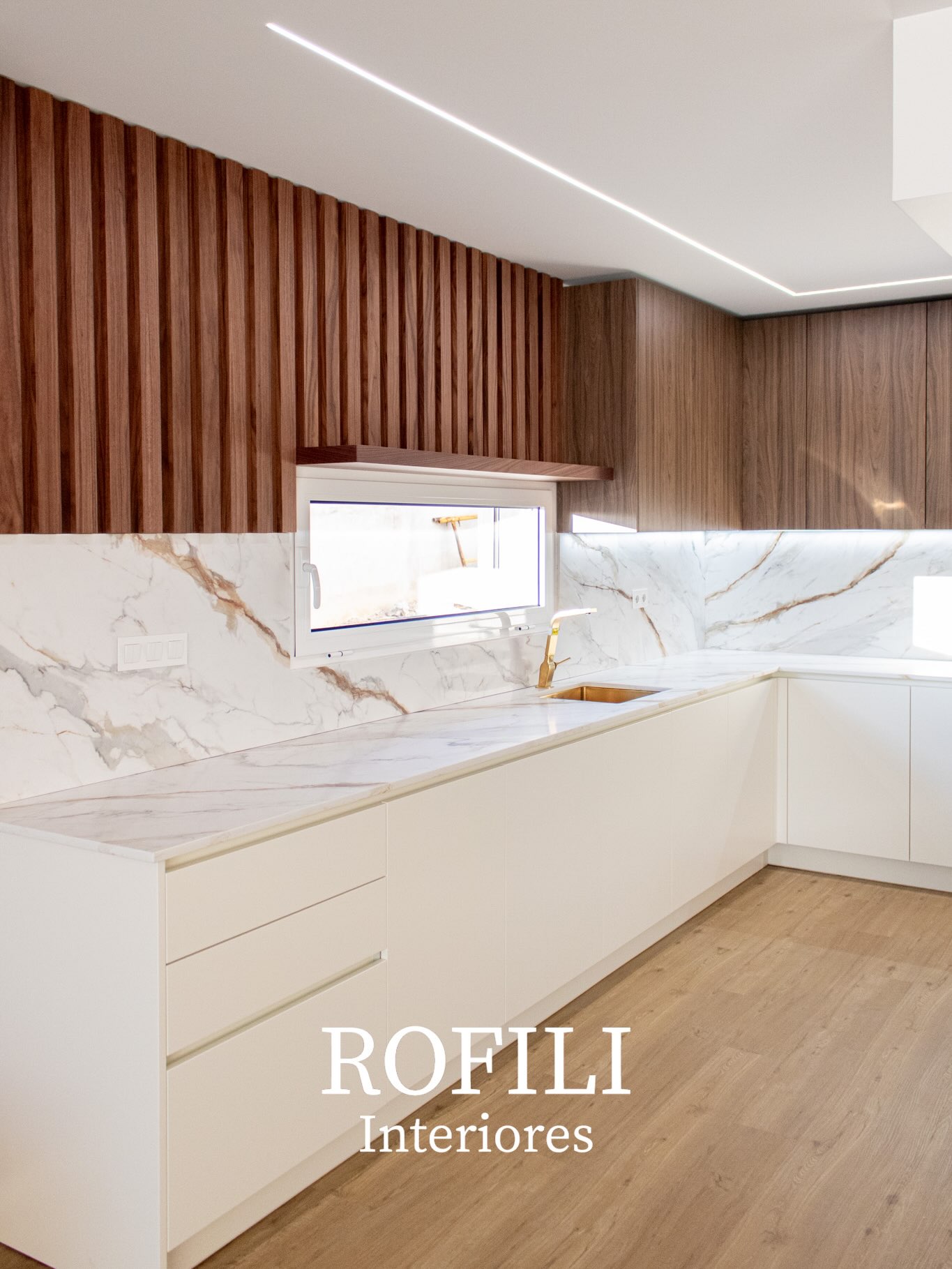 Cozinha por medida com frentes brancas, bancada clara, plano ripado em madeira e iluminação linear integrada