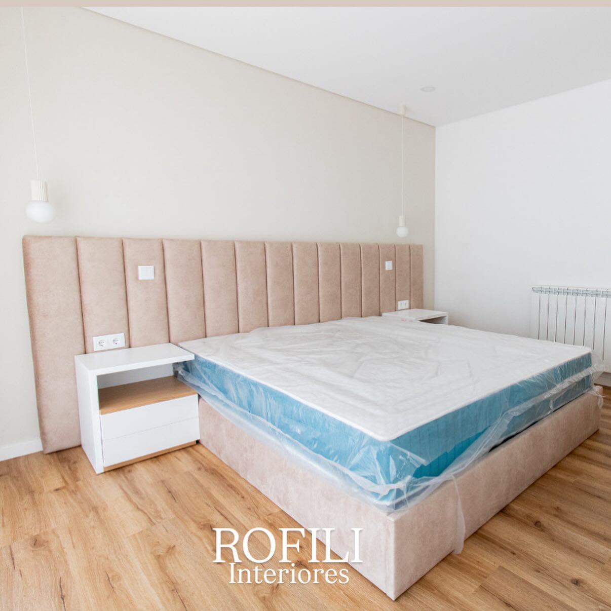 Quarto com cama estofada, cabeceira ampla que percorre a parede e mesas de cabeceira